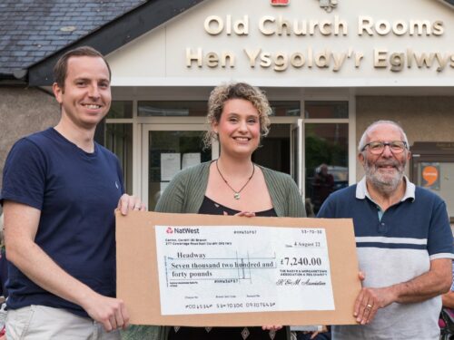Tom, Kat and David holding an oversived cheque outside the Old Church Rooms